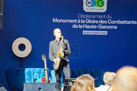 Photo for Toulouse, France - Aug. 31, 2023 - Structure relocation of Franois Verdier War Memorial: a musican is on stage to entertain the public during the pre show ahead of the event, playing the guitar - Royalty Free Image