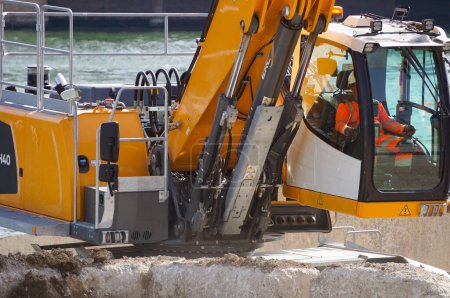 Foto de París, Francia - 6 de septiembre de 2023 - Una pala cargadora Komatsu amarilla en acción en un muelle, junto al agua, en una fábrica de cemento en Port de Tolbiac, puerto industrial junto al río Sena, en el distrito 13 - Imagen libre de derechos