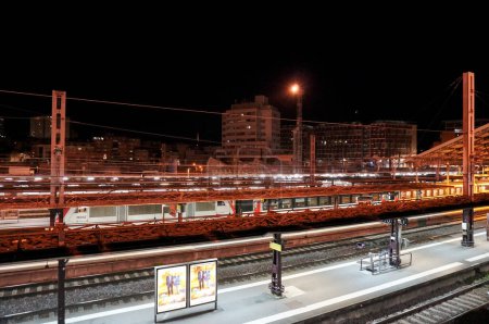 Foto de Toulouse, Francia - 11 de septiembre de 2023 - Vista general de las vías y plataformas ferroviarias de la estación de tren de Toulouse-Matabiau por la noche; un tren durmiente SNCF Intercits sale a la vanguardia - Imagen libre de derechos