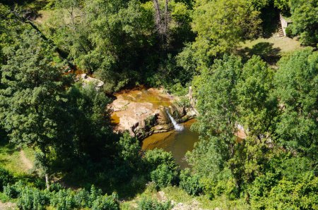 Foto de Vista superior de las cascadas en el Cañón de Bouzouls, un sitio geolocal y un parque natural en el valle del Lot, en el sur de Francia: el agua del río Dourdou se derrama sobre una cara de roca, en el bosque - Imagen libre de derechos