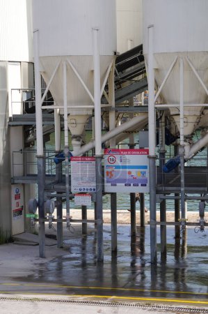 Foto de París, Francia - 5 de septiembre de 2023 - Silos blancos en una fábrica de cemento para la distribución de materiales en polvo en el puerto de Tolbiac, un puerto industrial junto al río Sena, en el distrito 13 de la capital - Imagen libre de derechos