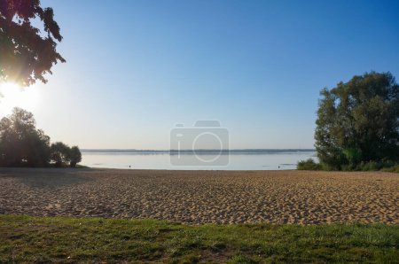 Photo for Graudot, France - Sept. 9, 2023 - Wild beach at sunset by the Lake of the Forest of Orient, near Troyes (Aube), looking towards Petite Italie Headland; the ground is covered with aquatic mosses - Royalty Free Image