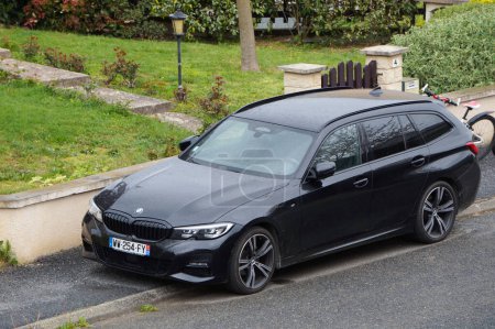 Photo for Aveyron, France - Feb. 1, 2023 - A black 2018 BMW 3 Series in hatchback version, an executive car produced by German premium automotive manufacturer BMW, parked on the curbside, in the shade of a tree - Royalty Free Image