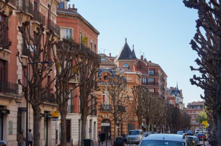 Téléchargez les photos : Toulouse, France - 1er février 2023 - Paysage urbain typique du Sud avec des bâtiments en briques rouges dans la perspective de la rue Ozenne bordée d'arbres, dans le quartier historique de Carmes à Toulouse - en image libre de droit
