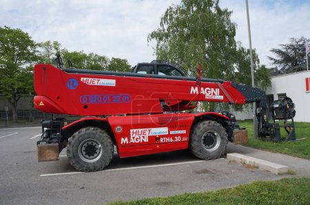 Téléchargez les photos : Toulouse, France - 3 mars 2023 - Un chariot télescopique de construction rouge avec flèche hydraulique, stationné à l'INSA ; le modèle est un RTH 6.30 rotatif produit par le fabricant italien de manutention Magni - en image libre de droit
