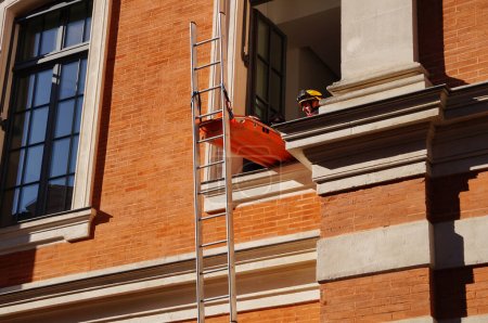 Foto de Toulouse, Francia - 7 de octubre de 2023 - Demostración en vivo del equipo de Búsqueda y Rescate en el Congreso Nacional de Bomberos: una víctima en una camilla es evacuada a través de una ventana con una escalera - Imagen libre de derechos