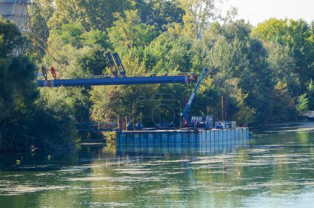 Téléchargez les photos : Toulouse, France - 7 octobre 2023 - Site de construction de Rapas : le pont à haubans est lancé au-dessus de l'eau ; il y a une grue et des opérateurs qui travaillent sur une plate-forme flottante, sur la Garonne - en image libre de droit