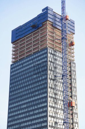 Foto de Lyon, Francia - 21 de noviembre de 2022 - Lugar de construcción de To-Lyon, el segundo rascacielos más alto del distrito financiero central de La Part-Dieu: la fachada de vidrio está flanqueada por una grúa torre y ascensores de carga - Imagen libre de derechos