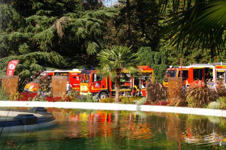 Téléchargez les photos : Toulouse, France - 7 octobre 2023 - Groupe de camions de pompiers exposés au public, sous les arbres, près d'un étang dans le Jardin du Boulingrin Grand-Rond, lors du Congrès national des pompiers français de 2023 - en image libre de droit