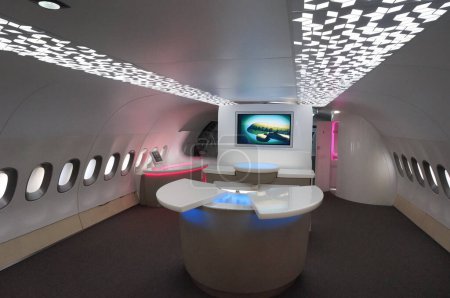 Photo for Toulouse, France - Nov. 21, 2023 - Luxurious lobby with modern furniture, inside the cabin of an Airbus A380, kept at Aeroscopia Museum; a TV screen displays a model serving at Qatar Airways - Royalty Free Image