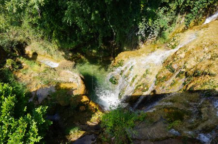 Téléchargez les photos : La cascade bien connue, coulant d'un promontoire rocheux dans une piscine naturelle donnant des reflets verts à l'eau, à Salles-la-Source, un village rural dans le département de l'Aveyron dans le sud de la France - en image libre de droit