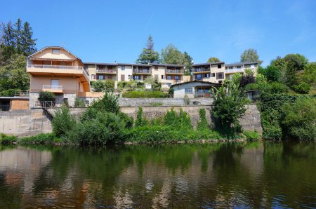 Foto de Espalion, Francia - 9 de agosto de 2023 - Casas de pueblo tradicionales construidas sobre un dique de piedra en el terraplén, a orillas del río Lot en Espalion, un casco antiguo ubicado en el departamento de Aveyron en el sur de Francia - Imagen libre de derechos