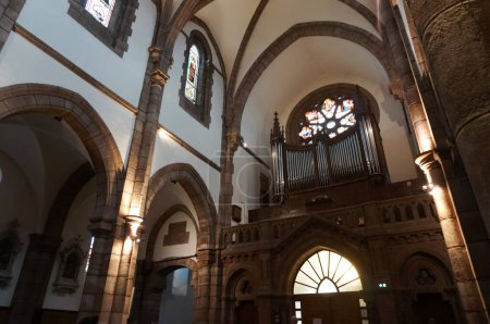 Foto de Espalion, Francia - 9 de agosto de 2023 - Órgano de balcón debajo del rosetón y por encima del portal, en la nave interior de San Juan Bautista, una iglesia neogótica de finales del siglo XIX - Imagen libre de derechos