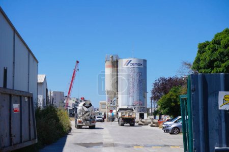 Foto de Toulouse, Francia - 9 de agosto de 2023 - La fábrica de cemento de CEMEX en el parque empresarial de Toulouse Arospace; a lo lejos, una grúa sobre el terreno de construcción de la futura estación de metro Montaudran Gare - Imagen libre de derechos