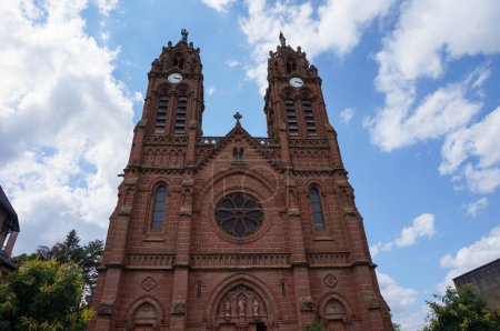 Téléchargez les photos : Espalion, France - 9 août 2023 - Saint Jean Baptiste, une église néo-gothique du XIXe siècle construite en grès rouge, avec deux clochers de 45 mètres surmontés de statues en bronze - en image libre de droit