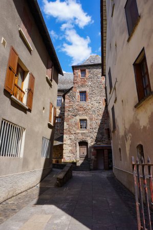 Téléchargez les photos : Espalion, France - 9 août 2023 - Une rue typique et étroite dans la ville médiévale d'Espalion, dans l'Aveyron rural ; l'édifice en pierre est ancien palais de justice du XVIe siècle, construit dans le style Renaissance - en image libre de droit