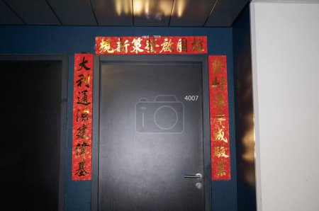 Téléchargez les photos : Toulouse, France - 15 février 2024 - Décorations autour d'une porte à l'entrée de l'appartement d'un étudiant chinois, à l'occasion du Nouvel An 2024 du Dragon ; les rubans rouges comportent des caractères mandarin - en image libre de droit