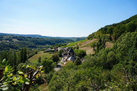 Foto de Fontcoussergues, Francia - 16 de agosto de 2023 - Vista desde la ladera de la iglesia de Saint-Austremoine y la aldea de Fontcoussergues en el valle, en la comuna de Salles-la-Sources, en la Aveyron rural - Imagen libre de derechos