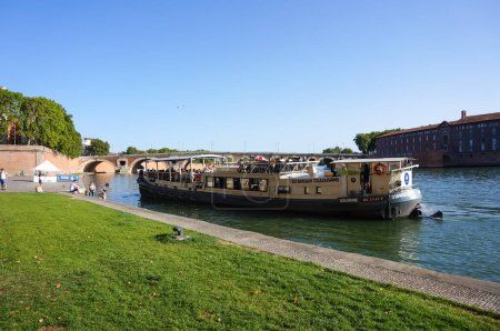 Téléchargez les photos : Toulouse, France - 9 août 2023 - Une péniche touristique accoste au port de Daurade, sur la Garonne, en aval du Pont-Neuf et devant Htel-Dieu Saint-Jacques, un vieil hôpital de Saint-Cyprien - en image libre de droit