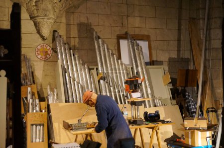 Téléchargez les photos : Albi, France - 18 février 2024 - Un artisan expérimenté sur le site de restauration d'un ancien orgue de balcon, réparant des tuyaux, à l'intérieur de la Collégiale Saint-Salvi, dans la zone du patrimoine mondial - en image libre de droit