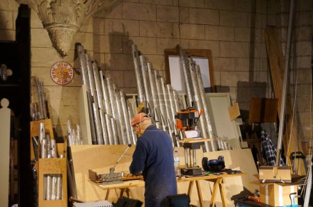 Téléchargez les photos : Albi, France - 18 février 2024 - Un artisan expérimenté sur le site de restauration d'un ancien orgue de balcon, réparant des tuyaux, à l'intérieur de la Collégiale Saint-Salvi, dans la zone du patrimoine mondial - en image libre de droit