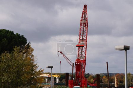 Téléchargez les photos : Labge, France - 2 décembre 2023 - Bôme métallique rouge d'une grue sur chenilles sur le chantier de Labge Viaduct, dans le parc d'affaires Palays, pour le prolongement de la ligne B du réseau de métro toulousain - en image libre de droit