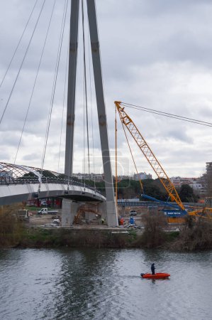 Téléchargez les photos : Toulouse, France - 23 février 2024 - Site de construction de Passerelle Rapas, passerelle suspendue reliant l'île Ramier à la rive gauche de la Garonne : vue sur le pont à haubans en acier - en image libre de droit