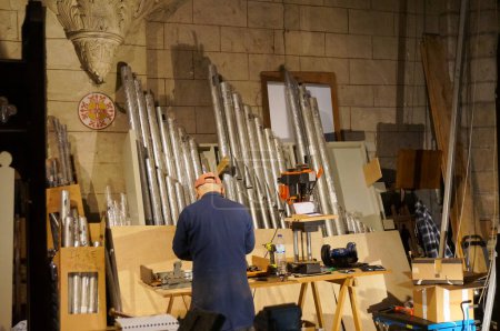 Foto de Albi, Francia - 18 de febrero de 2024 - Un artesano experimentado en el sitio de restauración de un antiguo órgano de balcón, reparando tuberías, dentro de la Iglesia Colegiata de Saint-Salvi, dentro de la zona del Patrimonio Mundial - Imagen libre de derechos