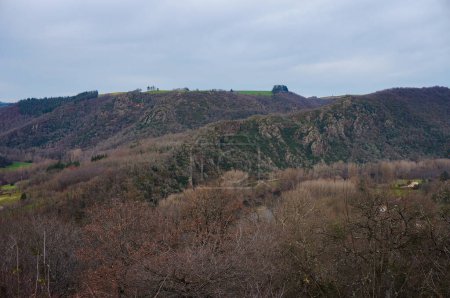 Photo for Ambialet, France - Jan. 28, 2024 - Mountains in the Valley of the Tarn River (Valle du Tarn); the slopes are covered with forests but have rocky outcrops and some steep cliffs, with fields on top - Royalty Free Image