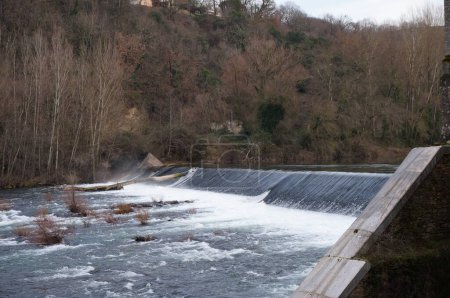 Foto de Saint-Jury, Francia - 28 de enero de 2024 - Agua que fluye sobre el vertedero de Les Avalats, en el río Tarn, en la presa de la central hidroeléctrica de Les Avalats, en una remota y boscosa zona rural - Imagen libre de derechos