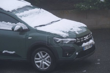 Foto de Aveyron, Francia - 10 de febrero de 2024 - Un Dacia Jogger en un estacionamiento, con el techo y el parabrisas parcialmente cubiertos de nieve en la madrugada después de una noche de ligera nevada, en una zona rural de Aveyron - Imagen libre de derechos