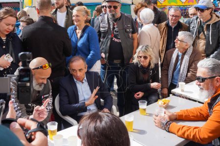 Photo for Bessieres, France - April 1, 2024 - Eric Zemmour chats with villagers at a caf during the Easter Giant Omelette, amid the campaign for the European elections; he is the president of "Reconquete!" - Royalty Free Image
