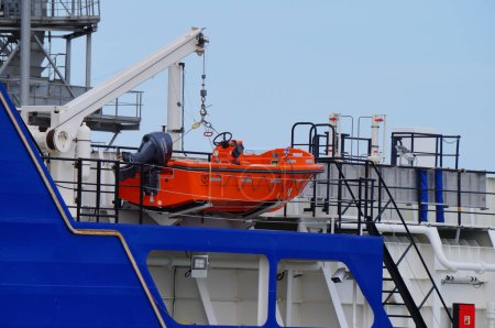 Photo for Port-la-Nouvelle, France - April 5, 2024 - A red lifeboat with a Japanese Yamaha engine, hanging on a ship crane, on board the brand-new Hydromer Ste electric hopper dredger of the Occitanie Region - Royalty Free Image