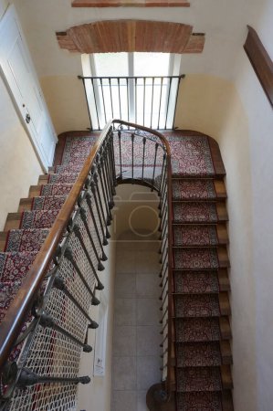 Photo for Gaillac, France - Feb. 1, 2024 - An elegant main staircase in a fine, historic manor house in a French classical, 17 or 18th-century style, with wooden handrail, floor carpet and lattice window - Royalty Free Image