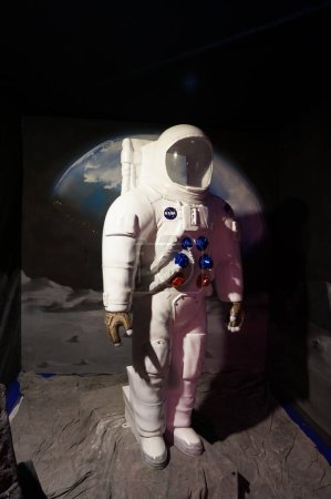 Téléchargez les photos : Aussonne, France - 19 avril 2024 - Mannequin simpliste d'un astronaute américain de la NASA sur la Lune, en combinaison spatiale, avec la Terre représentée à l'arrière, exposé à la Foire internationale de Toulouse - en image libre de droit