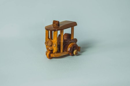 Una foto de cerca de un simple coche de juguete de madera llamado tuk tuk sobre un fondo plano y blanco.