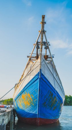 Balikpapan, Indonésie - 12 avril 2024. un classique voilier Bugis bleu et blanc amarré à un quai. Le bateau dispose d'une cabine avec garniture blanche et fenêtres.