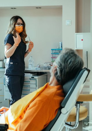 Téléchargez les photos : Femme médecin consulte avec le patient méconnaissable sur la procédure d'injections faciales - en image libre de droit