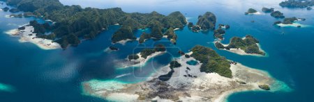 Photo for Limestone islands rise from the impressive seascape in Misool, Raja Ampat, Indonesia. These scenic islands' coral reefs, and the surrounding seas, support extraordinary marine biodiversity. - Royalty Free Image