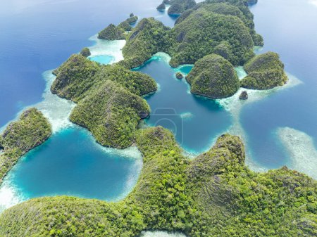 Zerklüftete Kalksteininseln erheben sich aus der tropischen Meereslandschaft von Raja Ampat. Diese Region Indonesiens ist aufgrund der außerordentlichen Artenvielfalt im Meer als das Herz des Korallendreiecks bekannt..