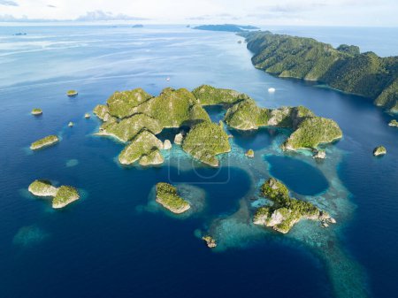Wunderschöne Kalksteininseln erheben sich aus der tropischen Meereslandschaft von Raja Ampat. Diese Region Indonesiens ist aufgrund der außerordentlichen Artenvielfalt im Meer als das Herz des Korallendreiecks bekannt..