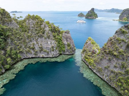 Die von Riffen gesäumten Kalksteininseln von Balbalol erheben sich aus der tropischen Meereslandschaft von Raja Ampat. Diese Region ist aufgrund der hohen Artenvielfalt im Meer als das Herz des Korallendreiecks bekannt..