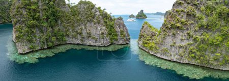 Photo for The limestone islands of Balbalol, fringed by reef, rise from Raja Ampat's tropical seascape. This region is known as the heart of the Coral Triangle due to the high marine biodiversity found there. - Royalty Free Image