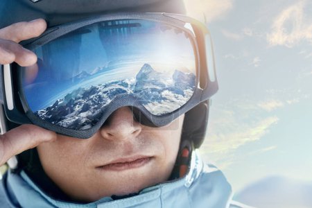 Photo for Close Up Of The Ski Goggles Of A Man With The Reflection Of Snowed Mountains. Man In The Background Blue Sky.  Winter Sports. - Royalty Free Image