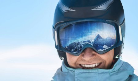 Photo for Man on the background blue sky. Wearing ski glasses. Winter Sports. A mountain range reflected in the ski mask. - Royalty Free Image