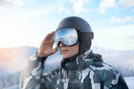 Photo for Close Up Of The Ski Goggles Of A Man With The Reflection Of Snowed Mountains. Man On The Background Blue Sky.  Winter Sports - Royalty Free Image