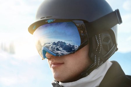 Photo for Portrait of man on the background blue sky holds ski goggles with the reflection of snowed mountains..Winter Sports - Royalty Free Image