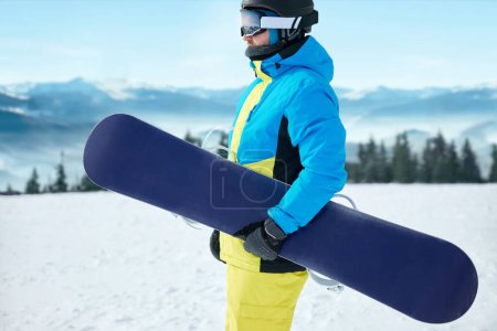 Photo for Portrait Of Snowboarder In The Ski Resort On The Background Of Mountains And Blue Sky Wearing Ski Glasses. Ski Goggles Of A Man  With The Reflection Of Snowed Mountains. - Royalty Free Image
