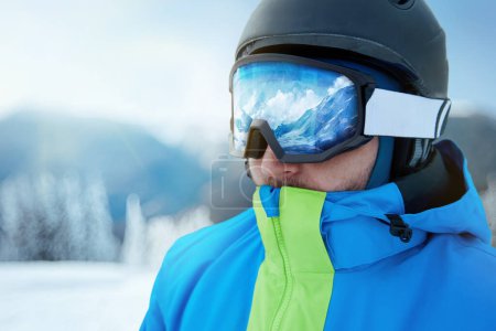 Photo for Close up of the ski goggles of a man with the reflection of snowed mountains. A mountain range reflected in the ski mask. Man on the background blue sky. Wearing ski glasses. Winter Sports. - Royalty Free Image