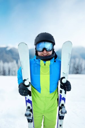 Photo for Portrait of a skier in the ski resort on the background of mountains and blue sky. Ski goggles of a man wearing ski glasses. Winter Sports - Royalty Free Image
